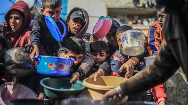 Das Foto zeigt Kinder im Gaza-Streifen. Sie halten leere Plastik-Schüsseln und Töpfe.
