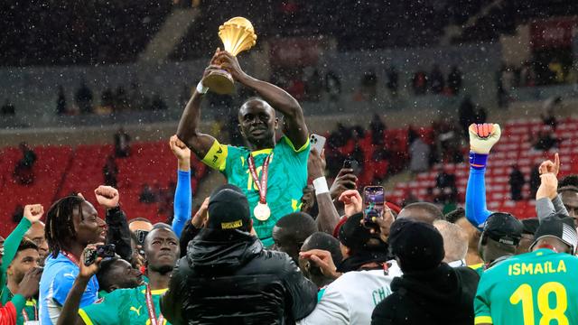 Ein Spieler von Senegal sitzt auf den Schultern von jemandem. Der Spieler hat eine Medaille um den Hals und hält einen Pokal hoch. 