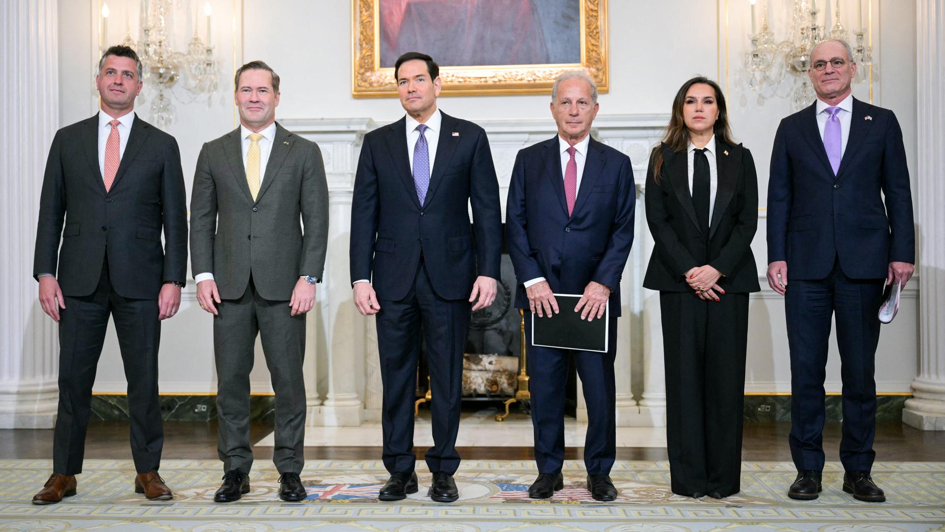 Fünf Männer und eine Frau stehen in einer Reihe nebeneinander. 