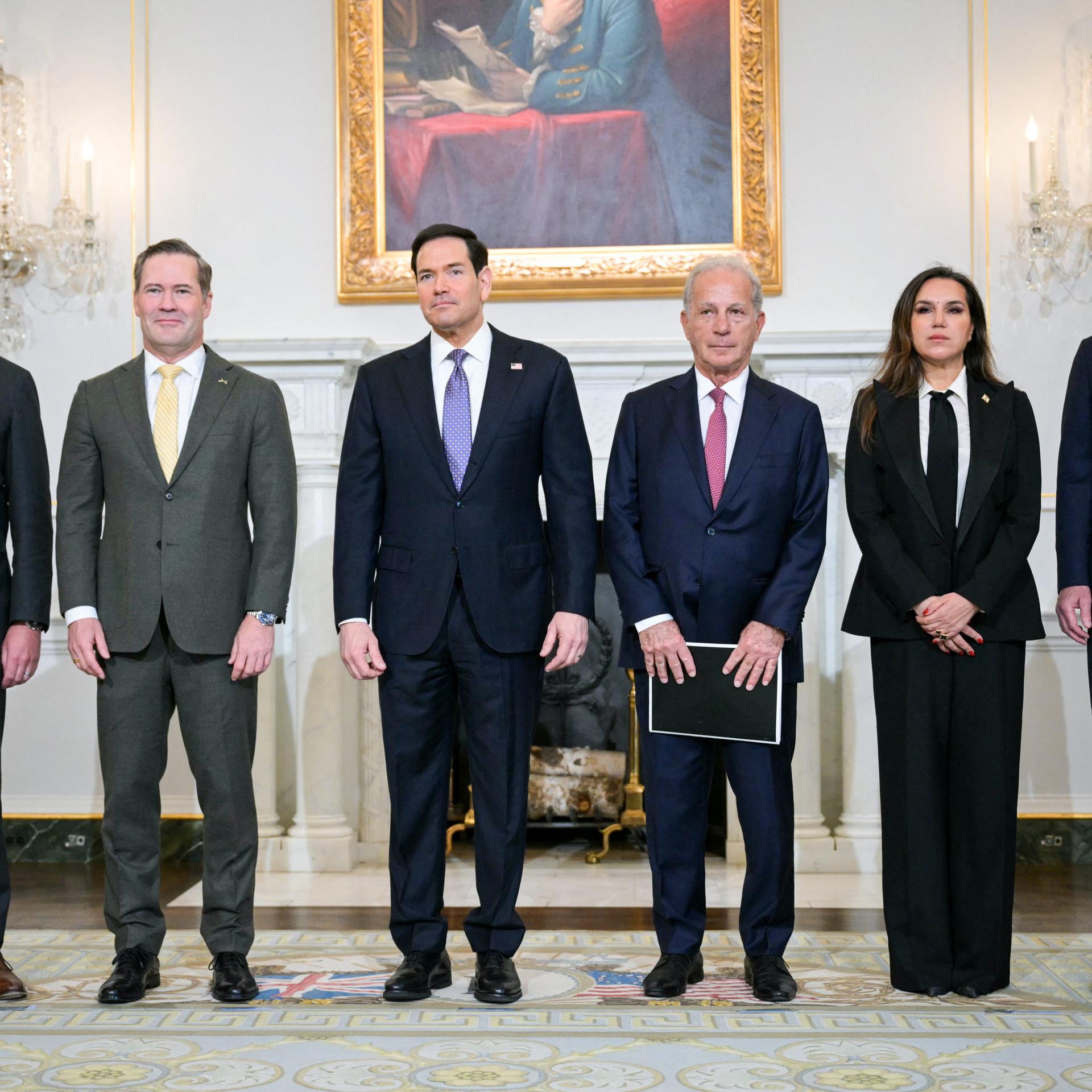 Fünf Männer und eine Frau stehen in einer Reihe nebeneinander. 