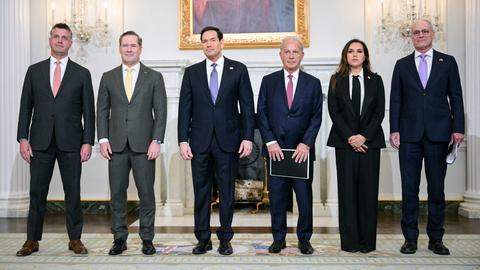 Fünf Männer und eine Frau stehen in einer Reihe nebeneinander. 