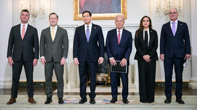 Fünf Männer und eine Frau stehen in einer Reihe nebeneinander. 