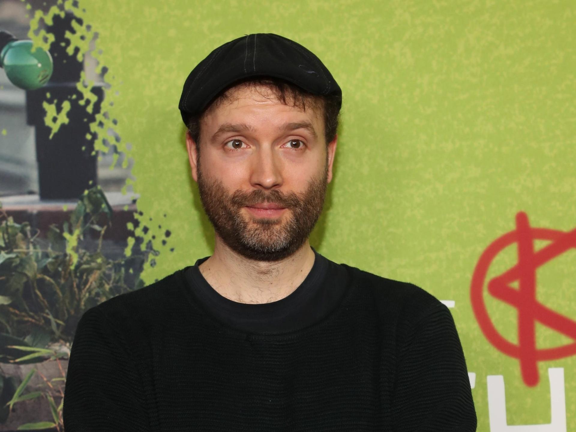 Marc-Uwe Kling trägt eine Kappe und hat die Arme vor der Brust verschränkt.