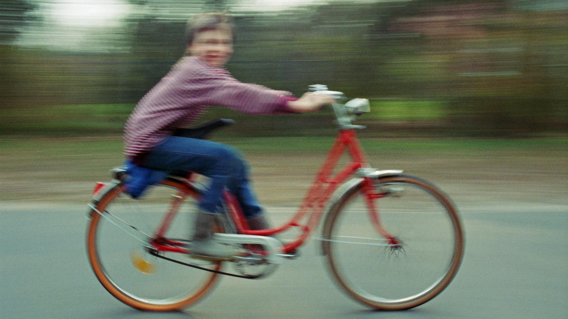 Durch Bewegungsunschärfe verschwommenes Bild eines Kindes, das auf einem Fahrrad fährt Durch Bewegungsunschärfe verschwommenes Bild eines Kindes, das auf einem Fahrrad fährt
