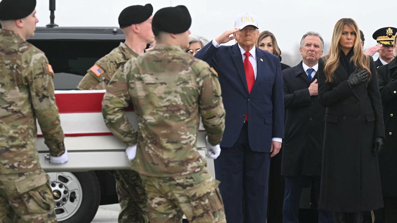 Donald Trump salutiert, während Soldaten einen in die US-Flagge gehüllten Sarg an ihm vorbeitragen.