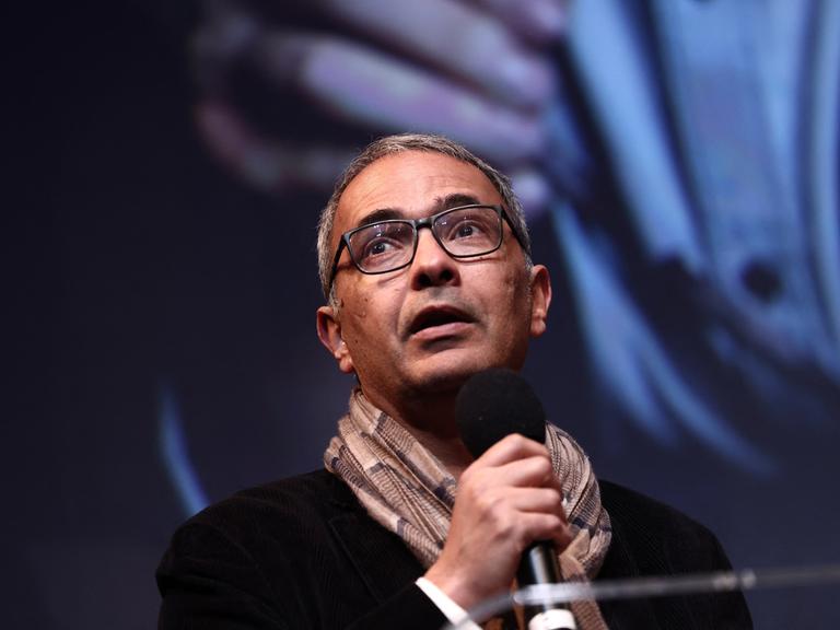 Kamel Daoud steht während einer Rede auf einer Bühne.