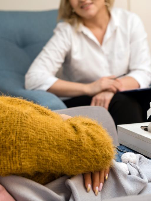 Psychologin, die mit einer Patientin spricht. Links im Bild die Patientin mit geschlossenen Augen, rechts die Psychologin. 