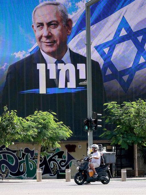 Ein Motorroller fährt in Tel Aviv an einer Plakatwand vorbei, auf der die Wahlwerbung von Premierminister Benjamin Netanjahu zu lesen ist.