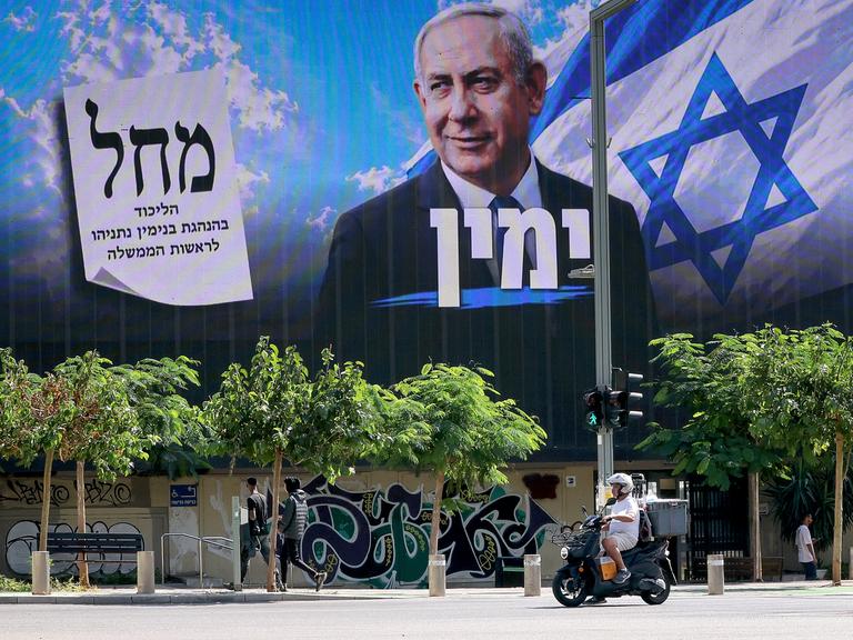 Ein Motorroller fährt in Tel Aviv an einer Plakatwand vorbei, auf der die Wahlwerbung von Premierminister Benjamin Netanjahu zu lesen ist.