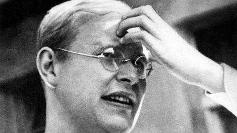 Der NS-Widerstandskämpfer und Pazifist Dietrich Bonhoeffer auf einer undatierten Aufnahme. Er trägt eine Brille, mit kleinen, ovalen Gläsern und hat seine linke Hand an der Stirn.