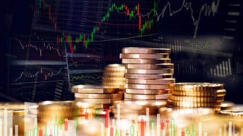 Stapel mit Münzen und Grafiken mit Kursen weltweiter Finanzmärkte
