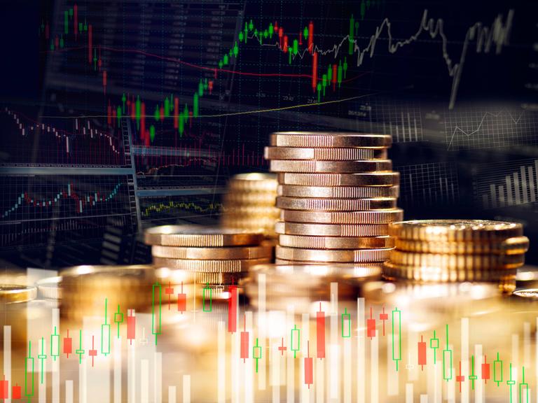 Stapel mit Münzen und Grafiken mit Kursen weltweiter Finanzmärkte Stapel mit Münzen und Grafiken mit Kursen weltweiter Finanzmärkte