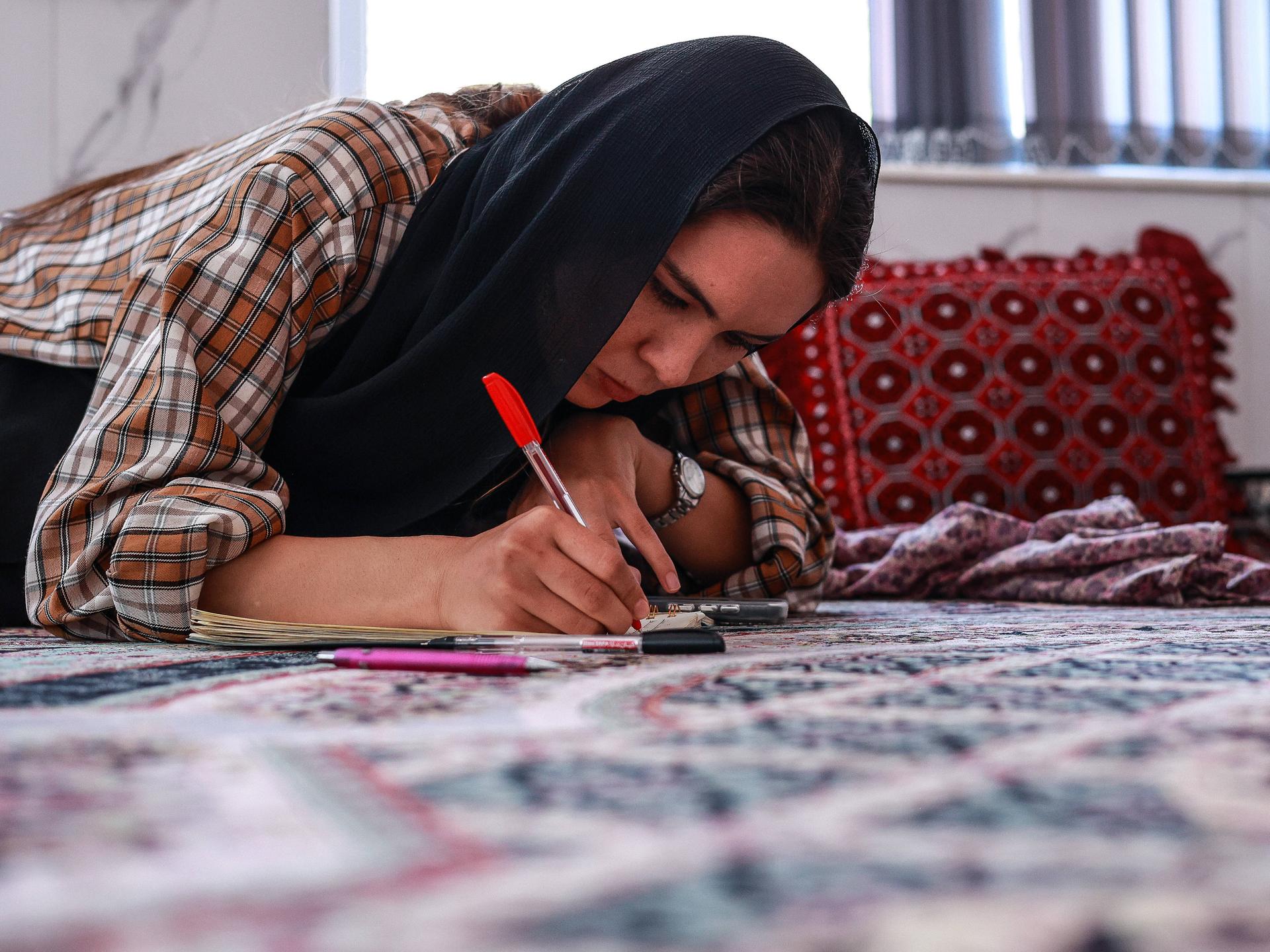 Eine junge Frau macht zu Hause in Herat ihre Englisch-Hausaufgaben, obwohl die Taliban Frauen ab dem zwölften Lebensjahr den Schulbesuch verboten haben.