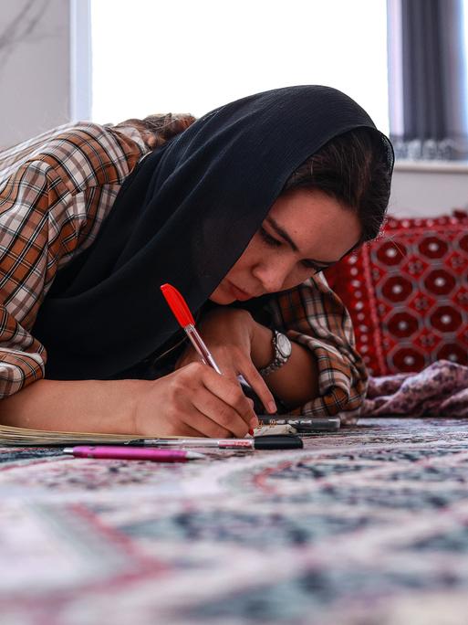 Eine junge Frau macht zu Hause in Herat ihre Englisch-Hausaufgaben, obwohl die Taliban Frauen ab dem zwölften Lebensjahr den Schulbesuch verboten haben.
