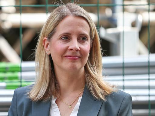 Die Bundesministerin für Wohnen, Stadtentwicklung und Bauwesen, Verena Hubertz (SPD), steht vor einem Bauzaun in Berlin