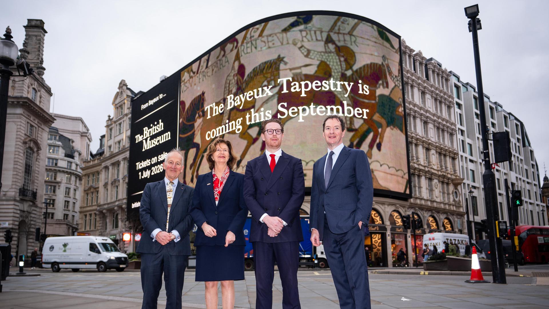 Der Direktor des British Museum, Dr Nicholas Cullinan, (3. v. links) mit weiteren Verantwortlichen vor einer Werbung für die Ausstellung ab September an einer Fassade am Picadilly Circus in London