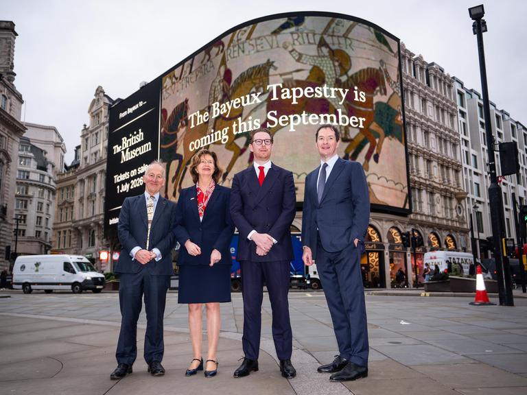 Der Direktor des British Museum, Dr Nicholas Cullinan, (3. v. links) mit weiteren Verantwortlichen vor einer Werbung für die Ausstellung ab September an einer Fassade am Picadilly Circus in London
