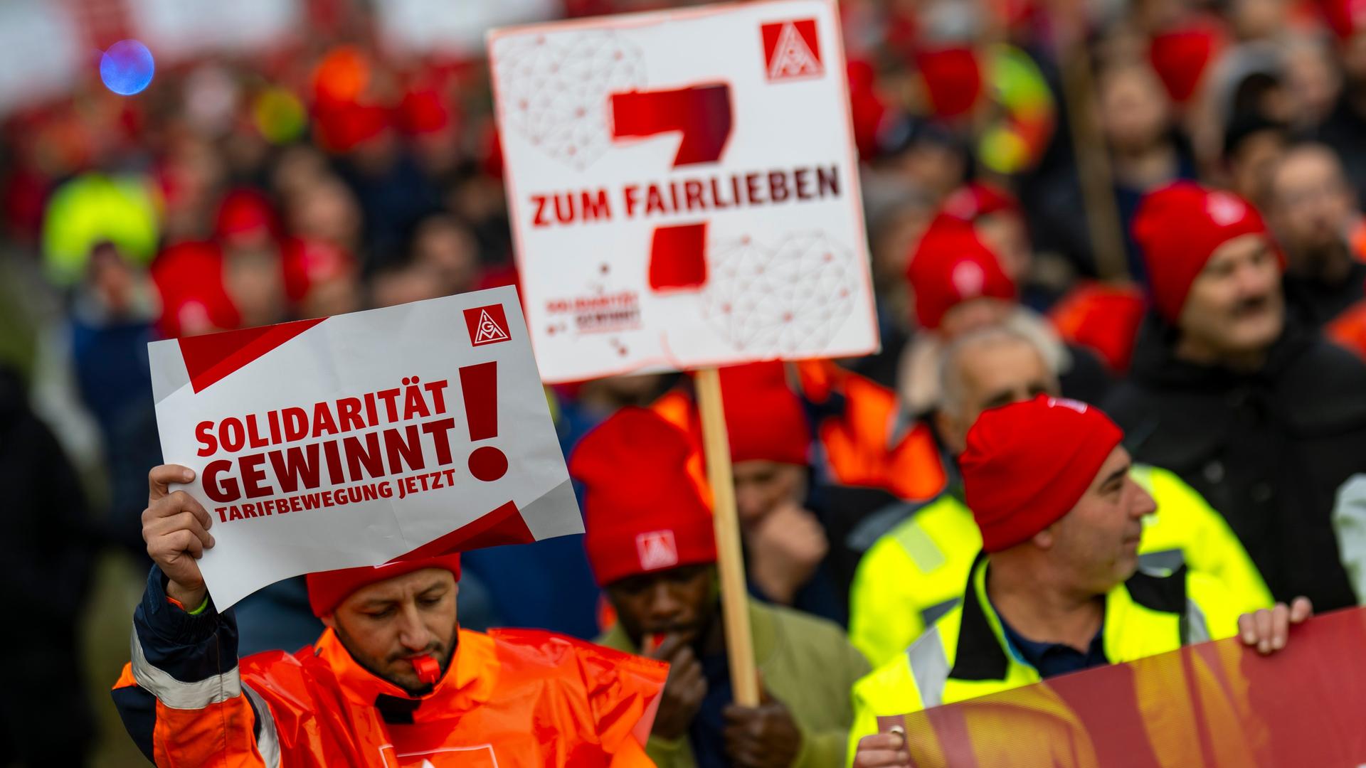 Mehrere Menschen protestieren mit Plakaten in der Hand und Trillerpfeifen. 