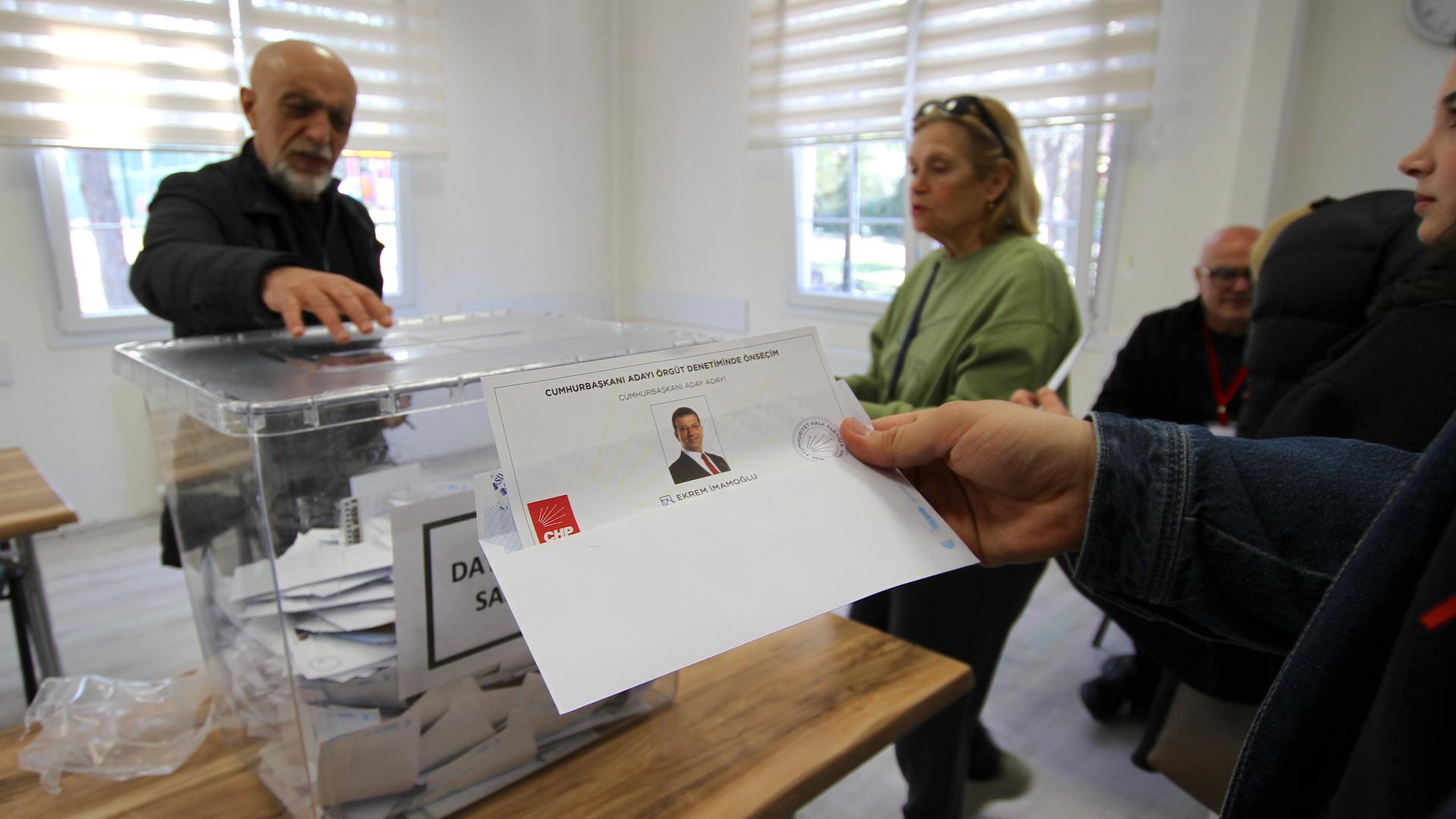 Eine durchsichtige Urne mit einem Zettel, das den CHP-Politiker İmamoğlu zeigt, steht in einem Wahllokal