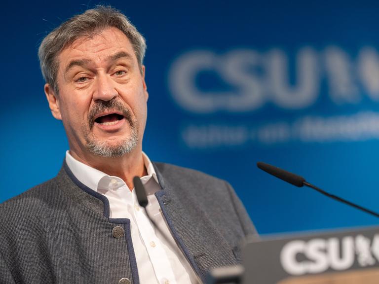 München: Markus Söder, Vorsitzender der CSU, spricht vor einem Mikrofon. Hinter ihm verschwommen der Schiftzug CSU.