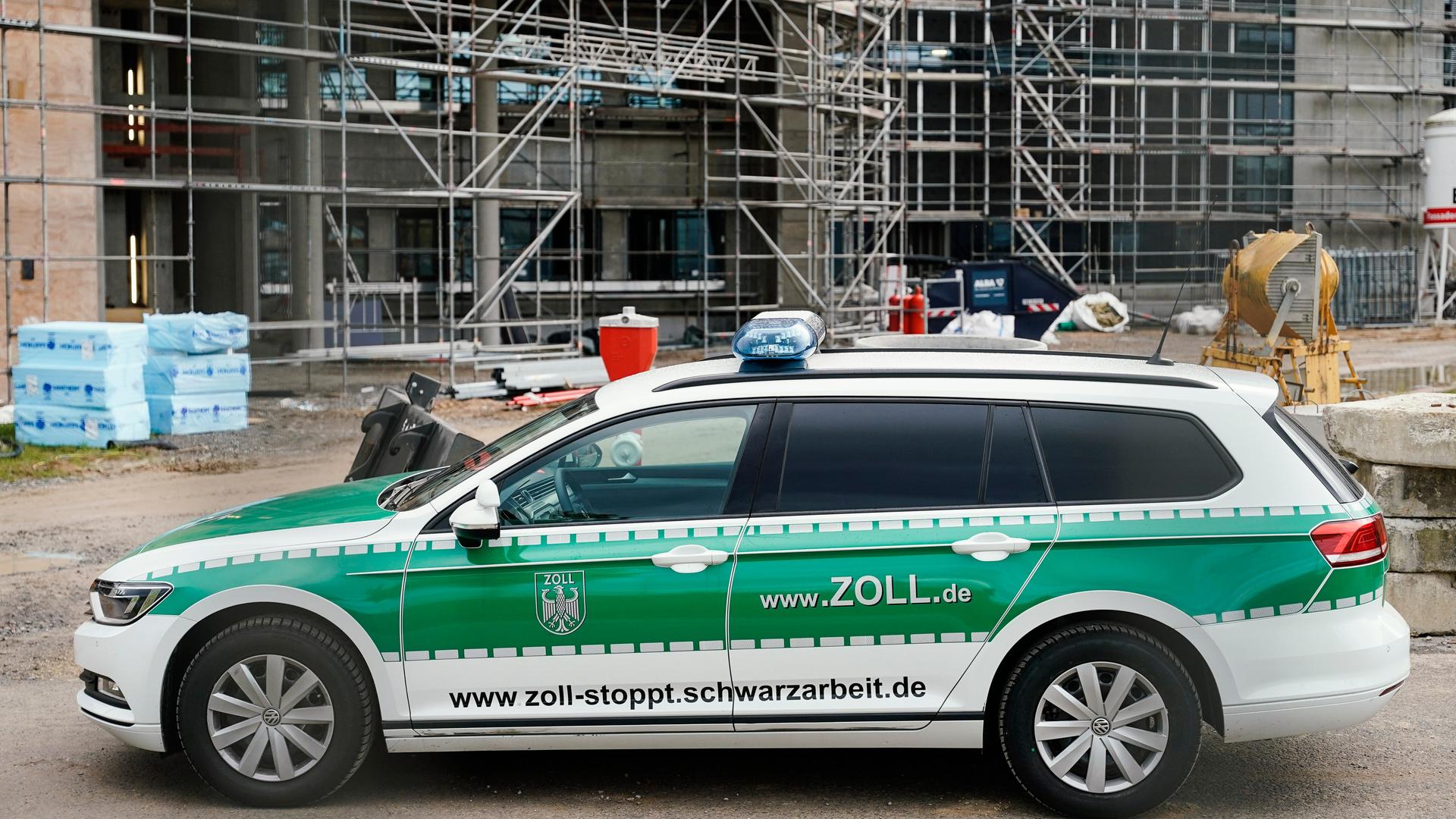 Ein Einsatzfahrzeug des Zolls mit der Aufschrift www.zoll-stoppt.schwarzarbeit.de steht bei einer Kontrolle auf einer Baustelle.