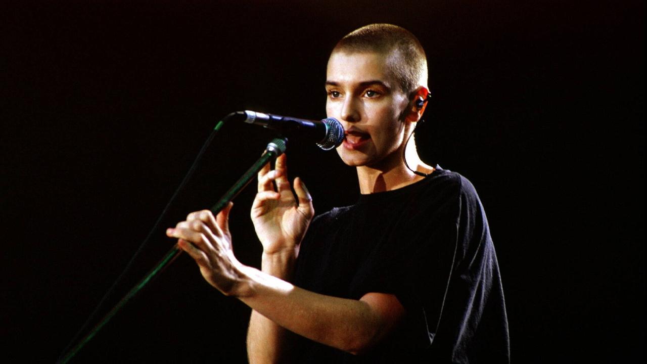 Sinéad O'Connor live in der Berliner Waldbühne 1990. Sie hält das Mikrofon mit beiden Händen.