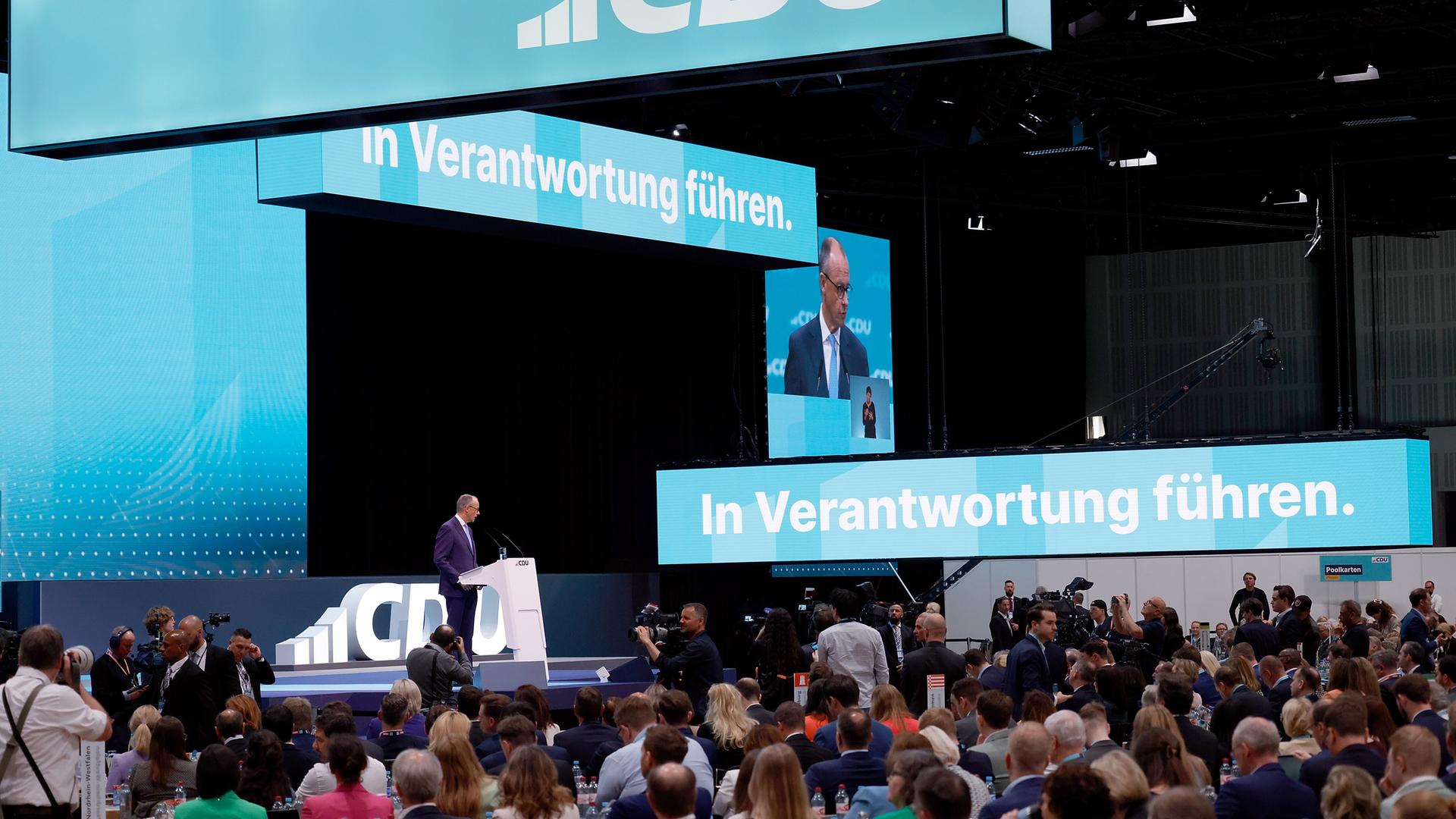 Friedrich Merz, CDU Bundesvorsitzender, spricht beim Bundesparteitag. Er steht auf der Bühne an einem weißen Rednerpult. Hinter ihm sieht man in Großbuchstaben CDU.