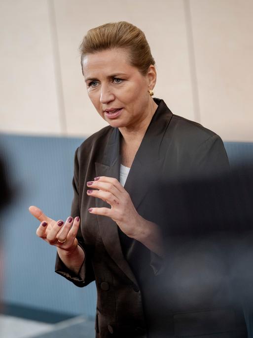Dänemarks Ministerpräsidentin Mette Frederiksen steht vor einer Gruppe und spricht.  