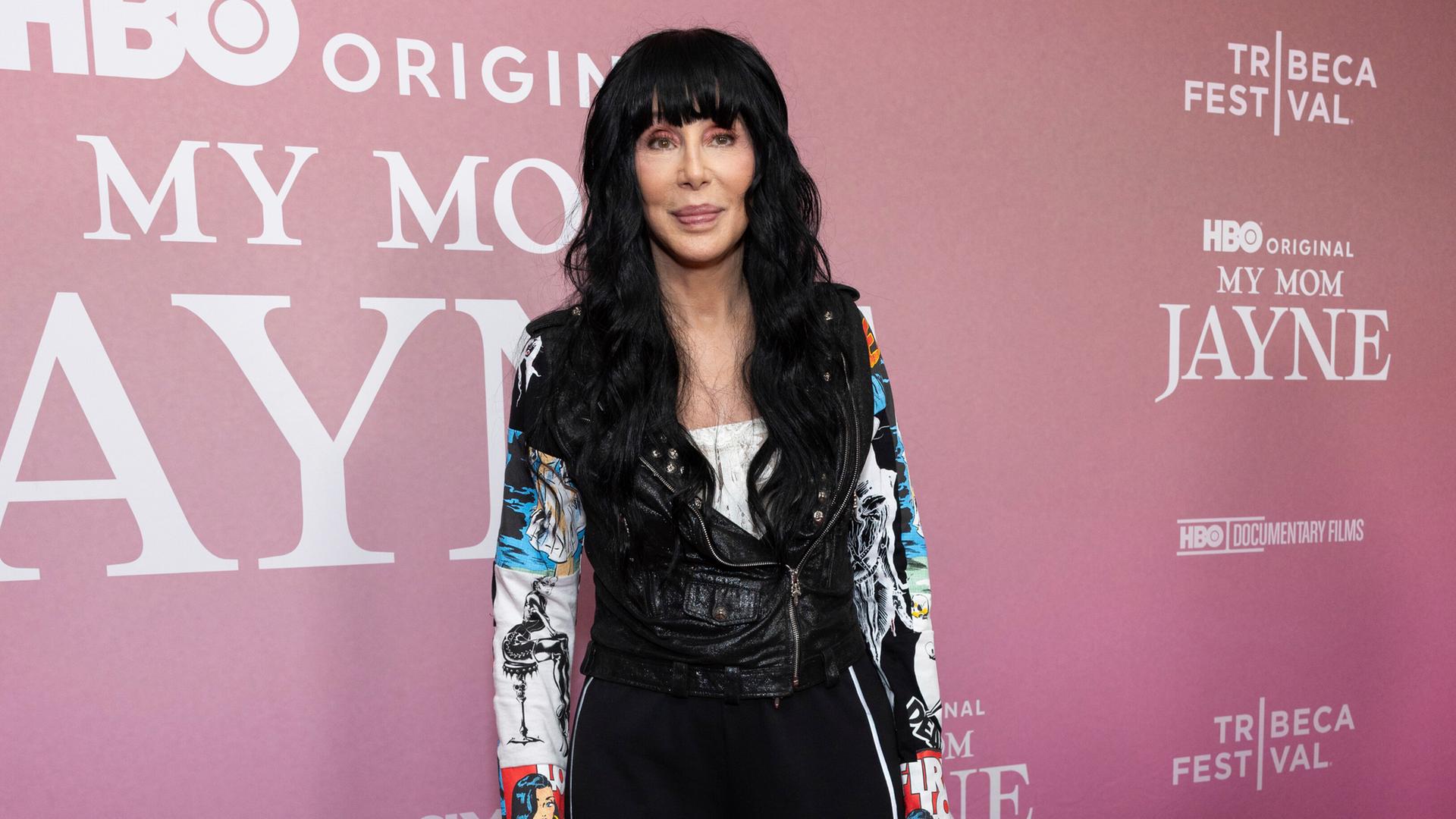 Die Sängerin Cher steht vor einer Sponsorenwand