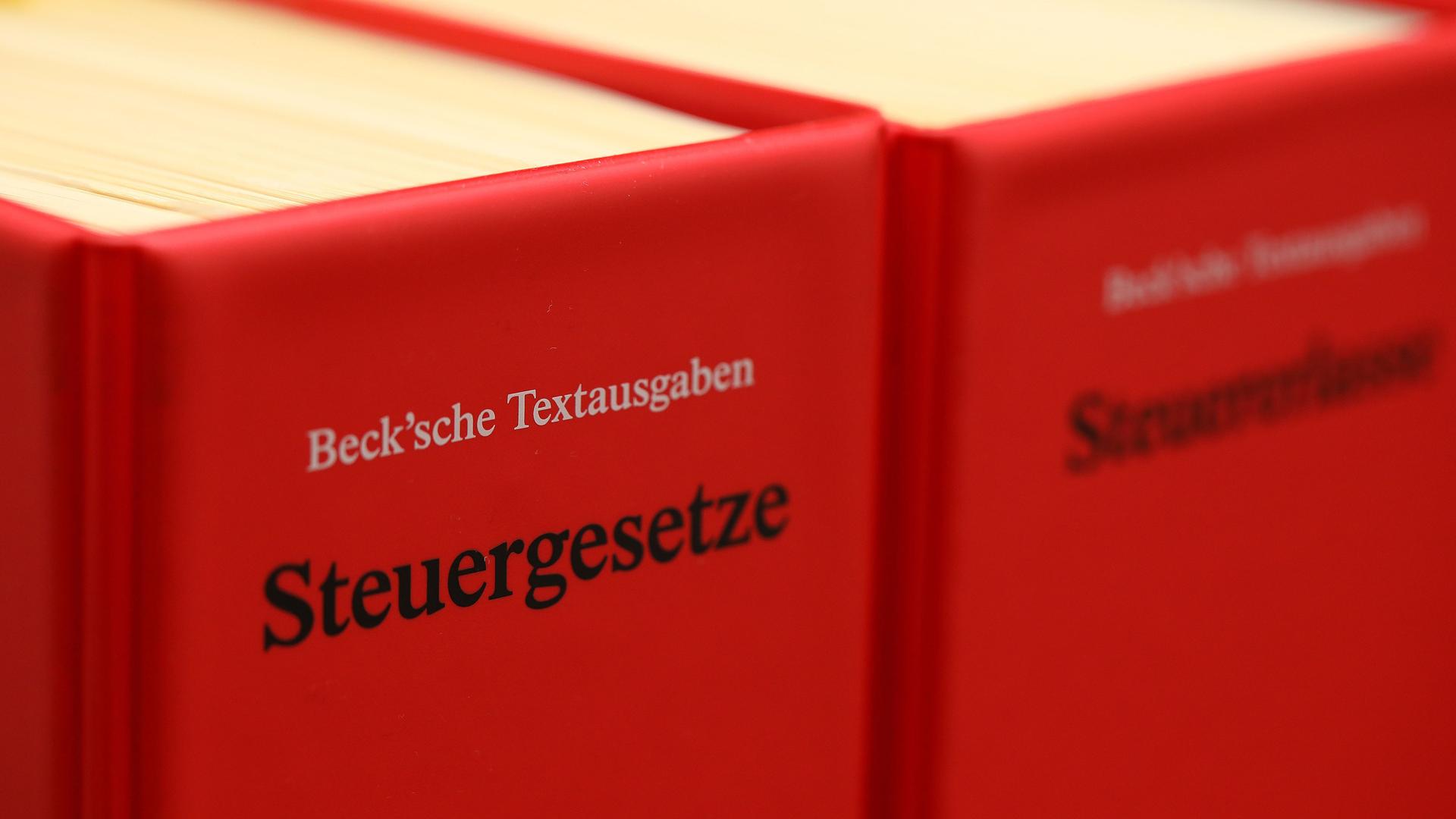 Zwei Steuergesetzbücher in rotem Einband stehen in einem Regal.