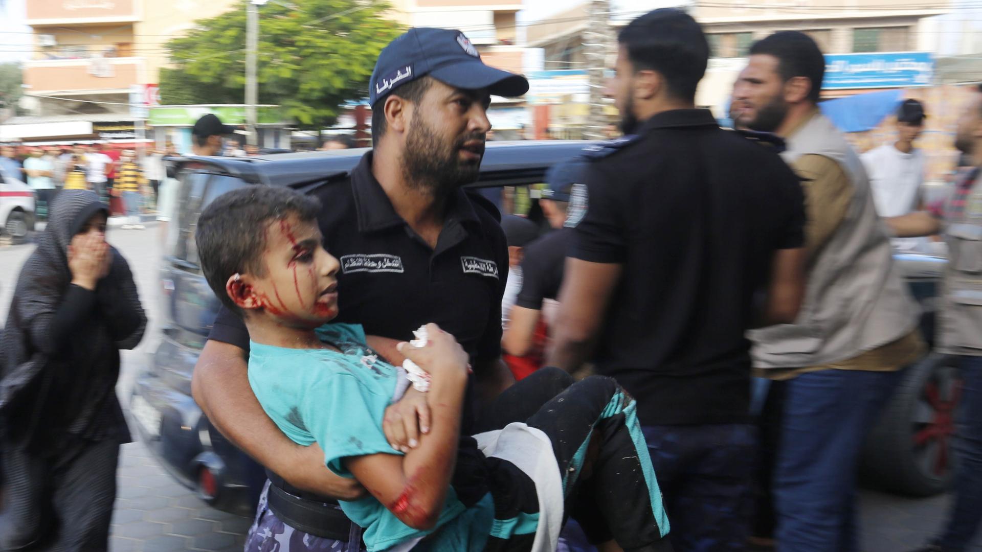 Nach einem Luftangriff auf ein Krankenhaus in Gaza trägt ein Mann ein Kind auf den Armen.