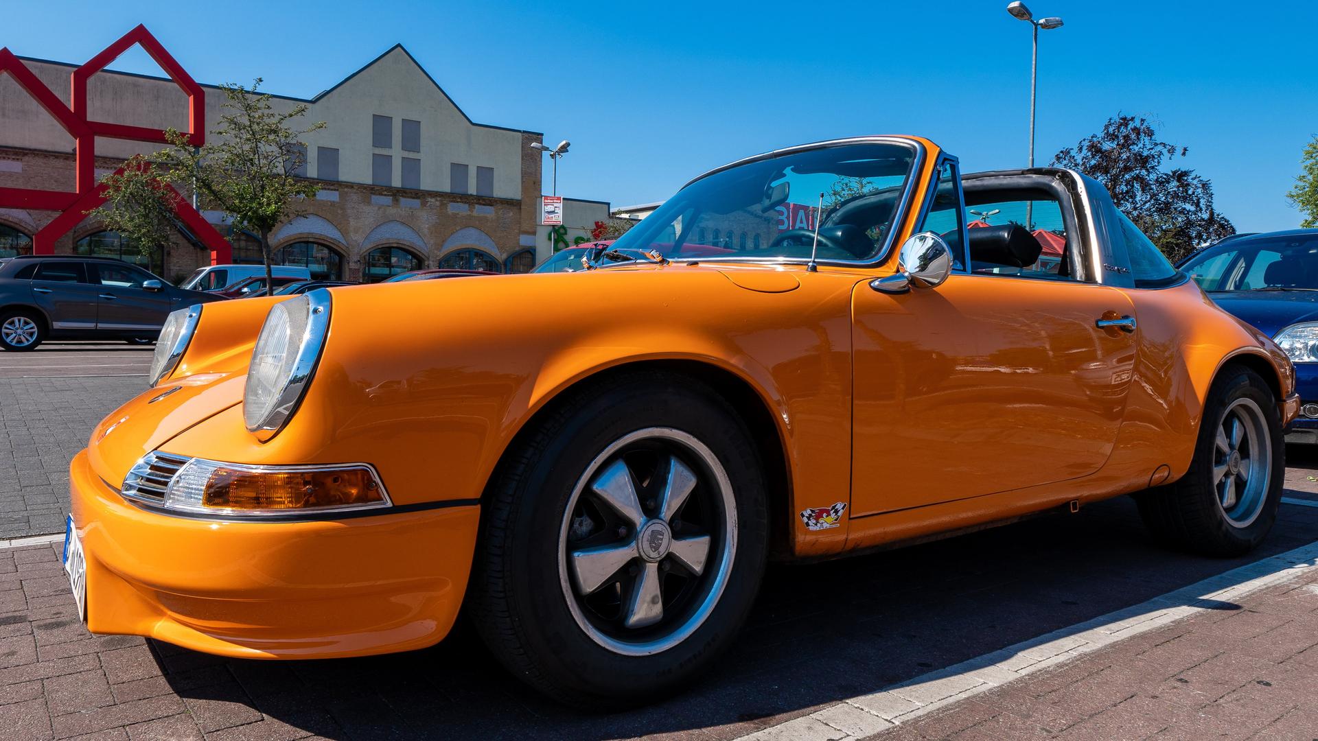 Ein orangefarbener Porsche 911 steht auf einem Parkplatz.