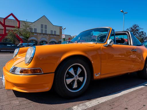 Ein orangefarbener Porsche 911 steht auf einem Parkplatz.