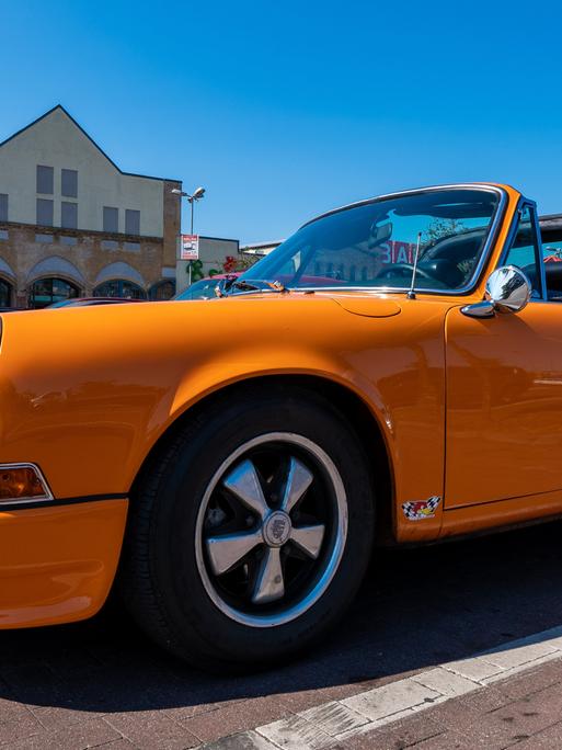Ein orangefarbener Porsche 911 steht auf einem Parkplatz.