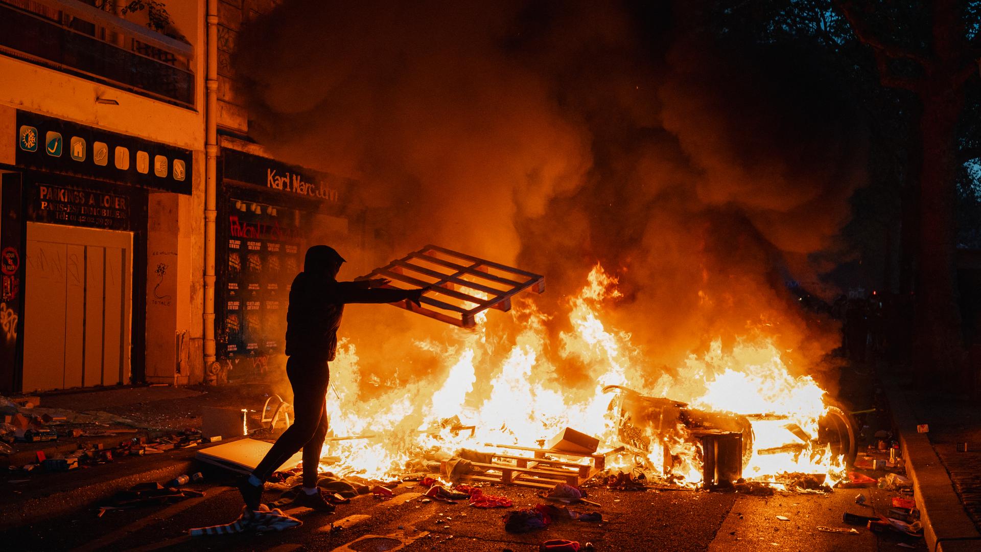 Ausschreitungen in Paris: Ein Demonstrant wirft eine Palette in ein Feuer.