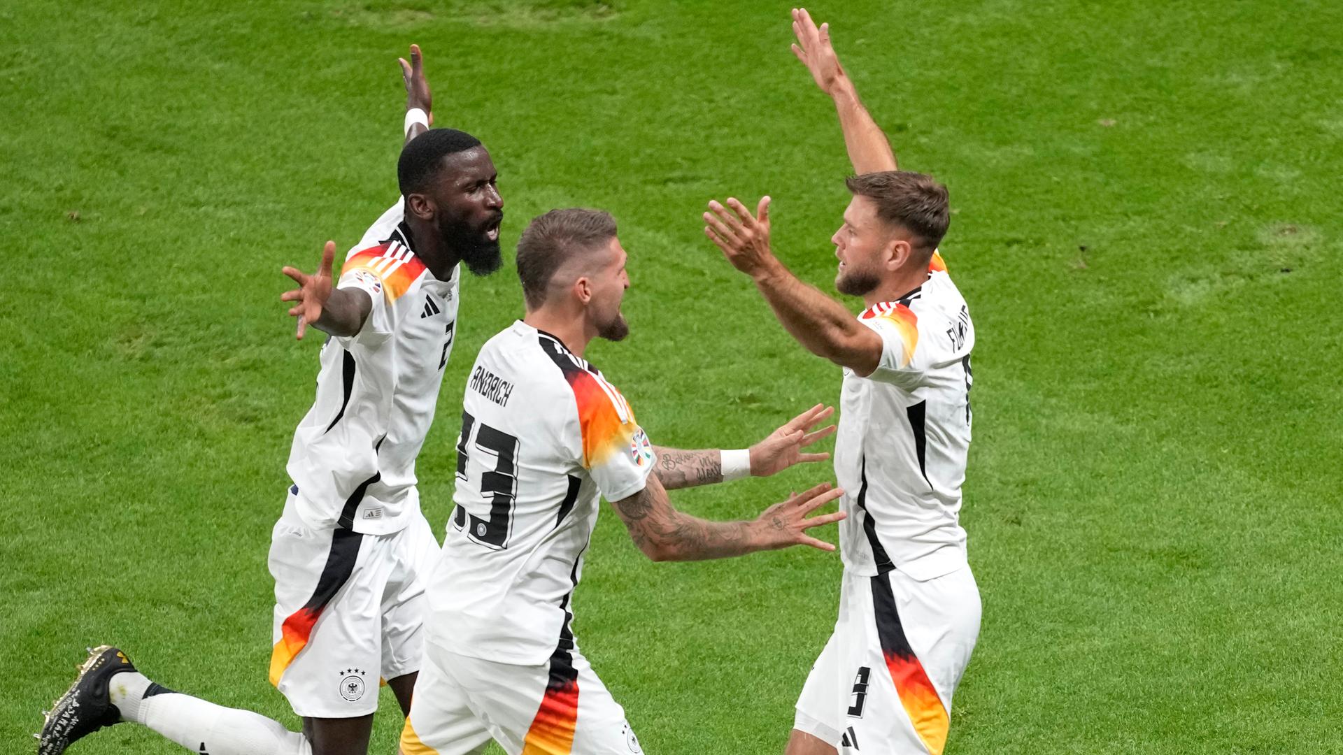 Die deutschen Nationalspieler Antonio Rüdiger und Robert Andrich laufen auf den Torschützen zum 1:1, Niclas Füllkrug (re.), zu. 