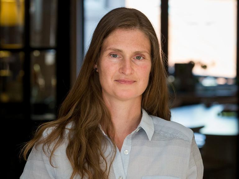 Barbara Promberger lächelt in die Kamera. Sie trägt ein hellblaues Hemd und hellbraunes, offenes Haar.