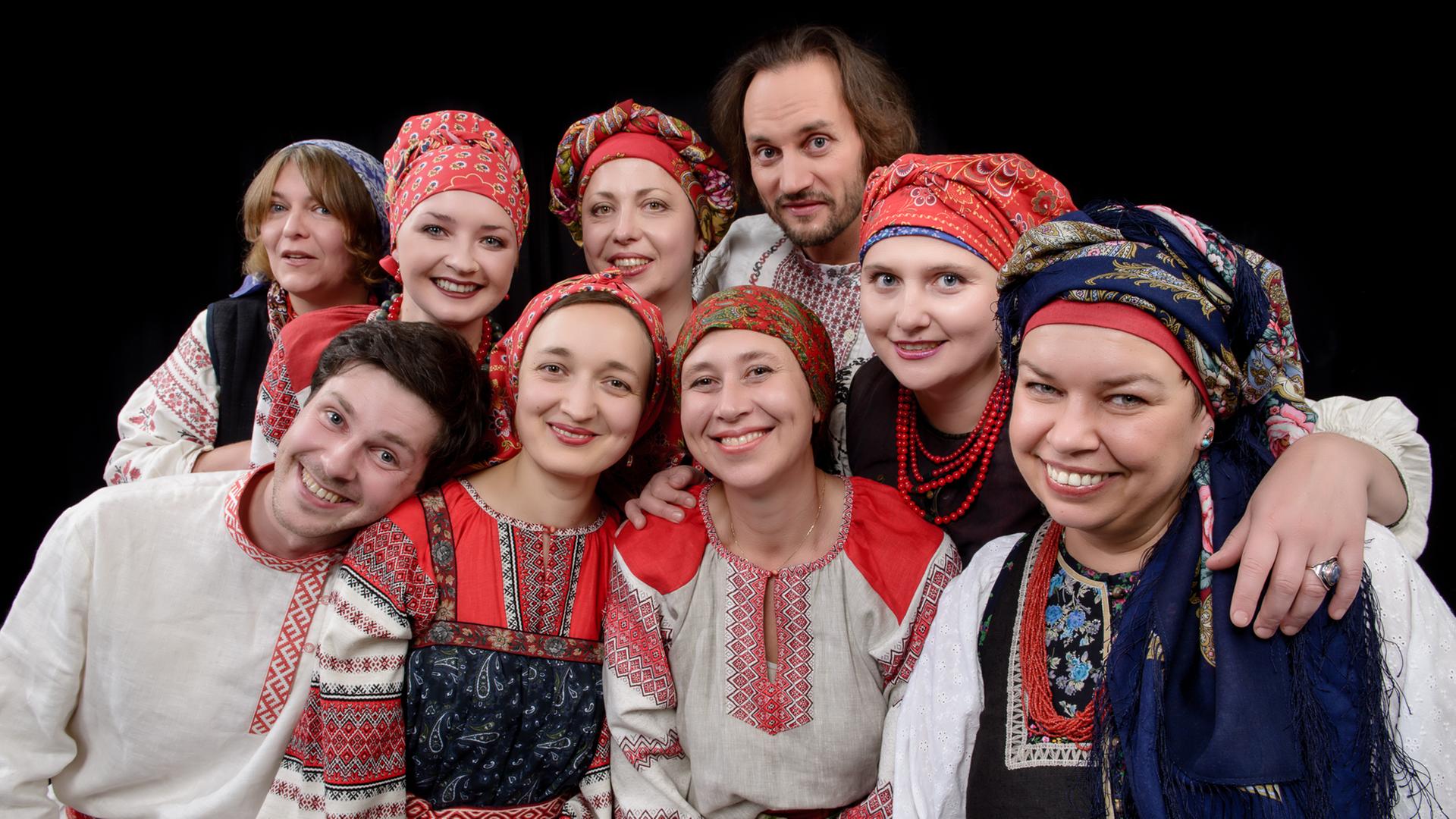 Eine Gruppe von Männern und Frauen in folkloristischer Kleidung stehen nebeneinander und lächeln in die Kamera