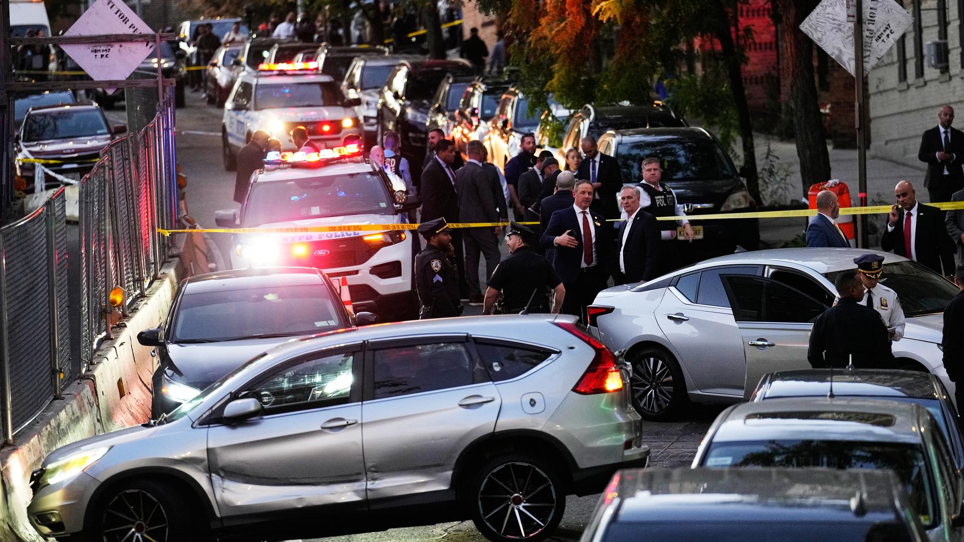 Das Bild zeigt einen großräumig abgesperrten Tatort auf einer Straße voller Autos, Polizeifahrzeugen und Ermittlern.
