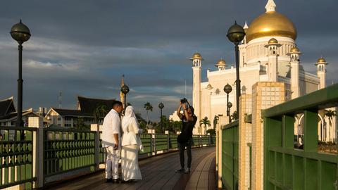 Ein frisch verheiratetes Paar lässt sich vor der Moschee Sultan Omar Ali Saifuddien in Brunei fotografieren, 2019.