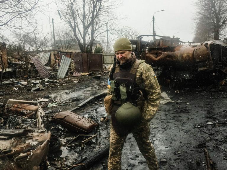 Ukrainische Soldaten inspizieren das Wrack einer zerstörten russischen Panzerkolonne auf einer Straße in Butscha, einem Vorort nördlich der Hauptstadt Kiew. 