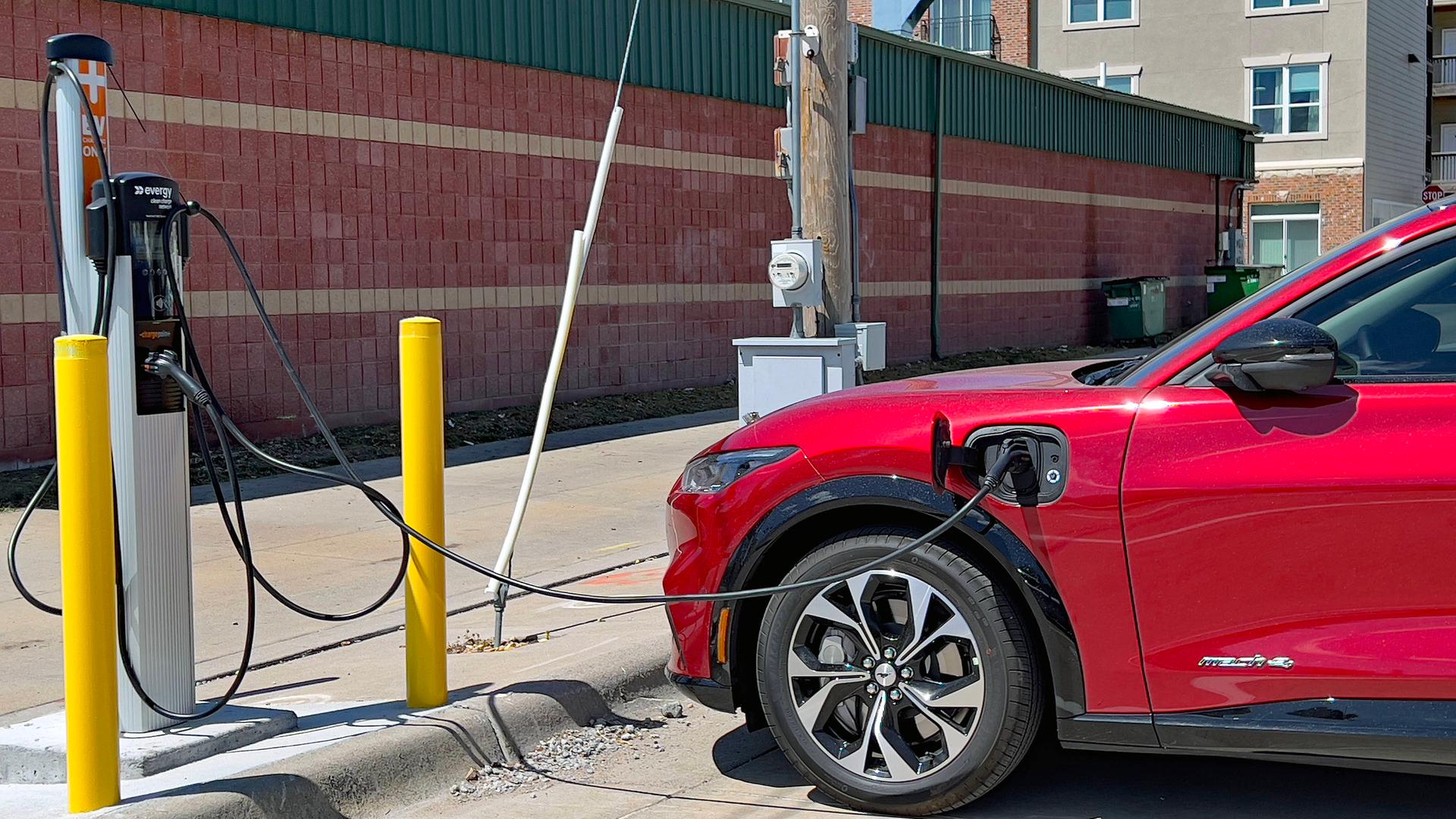 Ein roter Ford Mustang wird an einer Elektrotankstelle aufgeladen