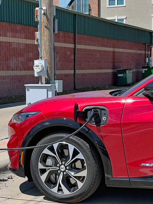 Ein roter Ford Mustang wird an einer Elektrotankstelle aufgeladen