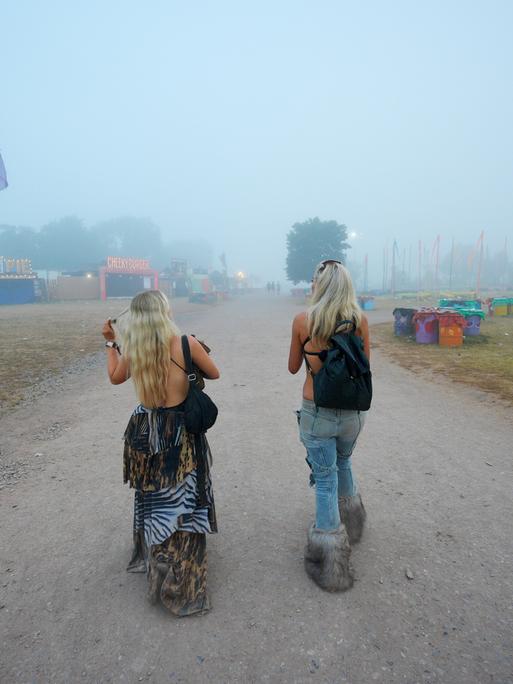 Zwei Besucherinnen sind von hinten zu sehen bei ihrem Weg zum Glastonbury-Festival 