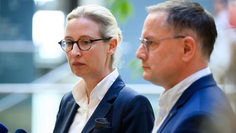 Zu sehen sind die beiden AfD-Politiker Alice Weidel und Tino Chrupalla. Sie blicken ernst.