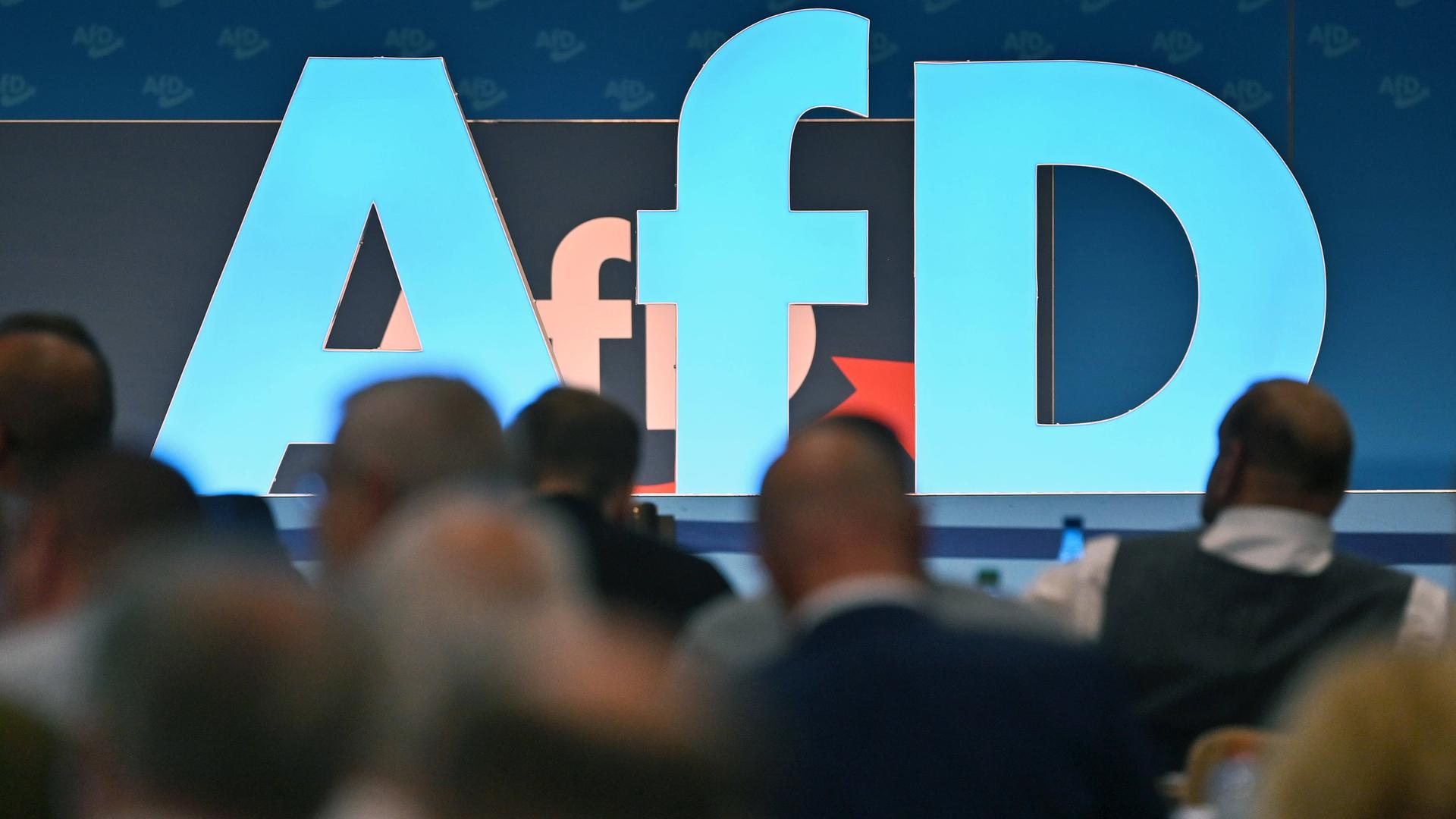 Blick auf blaues AfD-Logo, im Vordergrund sitzen die Delegierten. Der 14. Bundesparteitag der AfD war am 28.7.2023