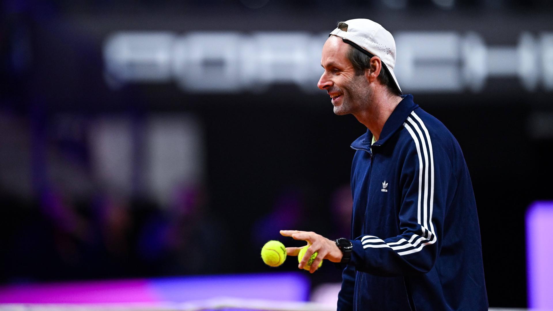 Torben Beltz von der Seite. Er lächelt und hat zwei Tennisbälle in der Hand. 