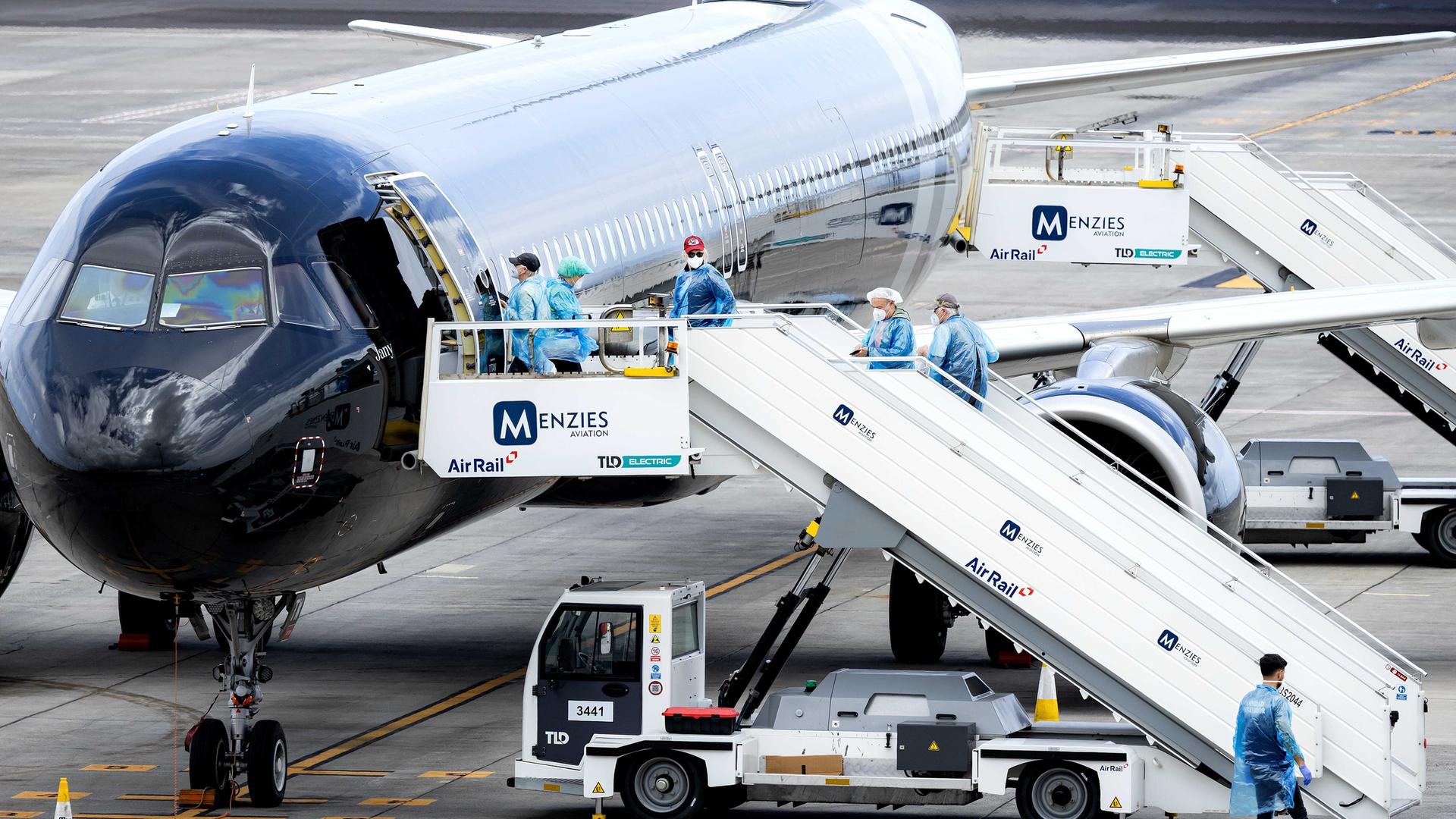Passagiere und Besatzungsmitglieder der "Hondius" werden ausgeflogen. Sie steigen in ein Flugzeug und tragen blaue Schutzanzüge und Masken.
      