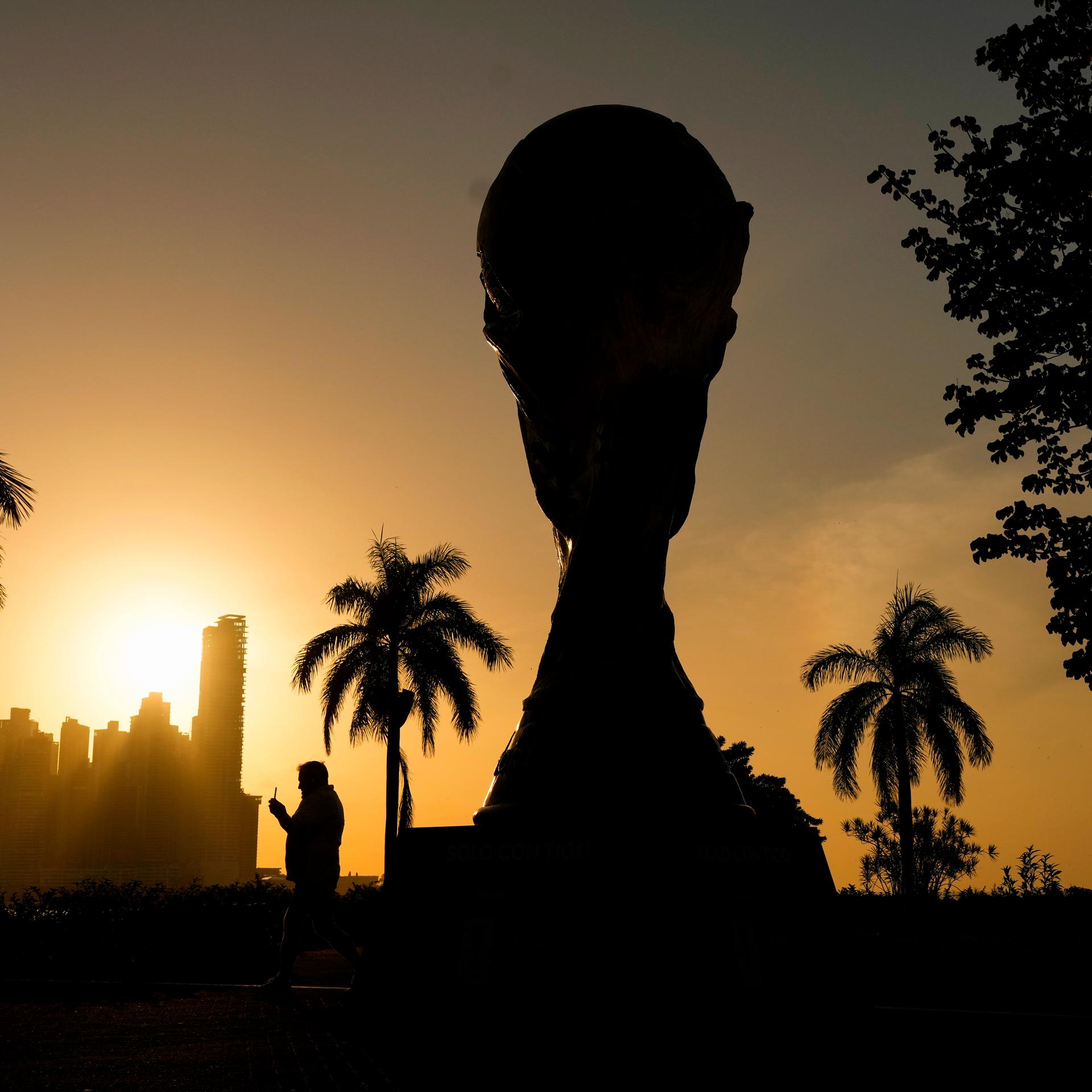 Eine Nachbildung des Fußball-WM-Pokals ist bei Sonnenuntergang im Gegenlicht zu sehen.