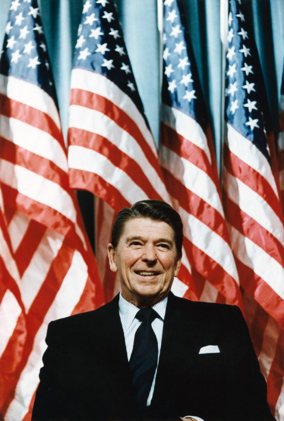Ronald Reagan steht vor aneinander gereihten US-Flaggen